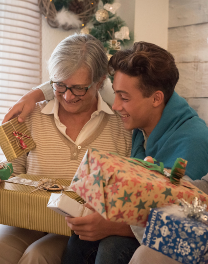 Older adult female and adult grandchild sharing holiday gifts