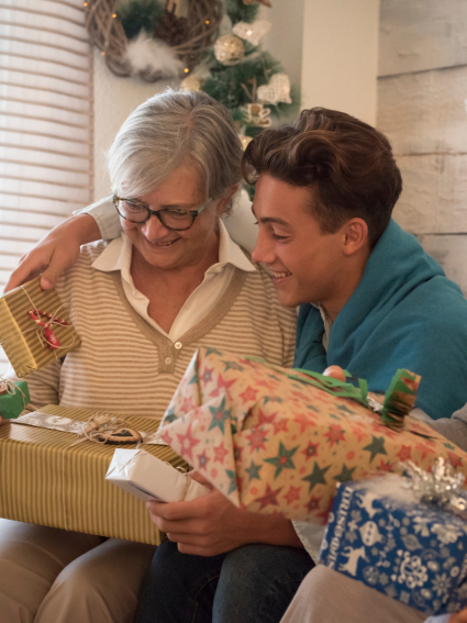 Older adult female and adult grandchild sharing holiday gifts